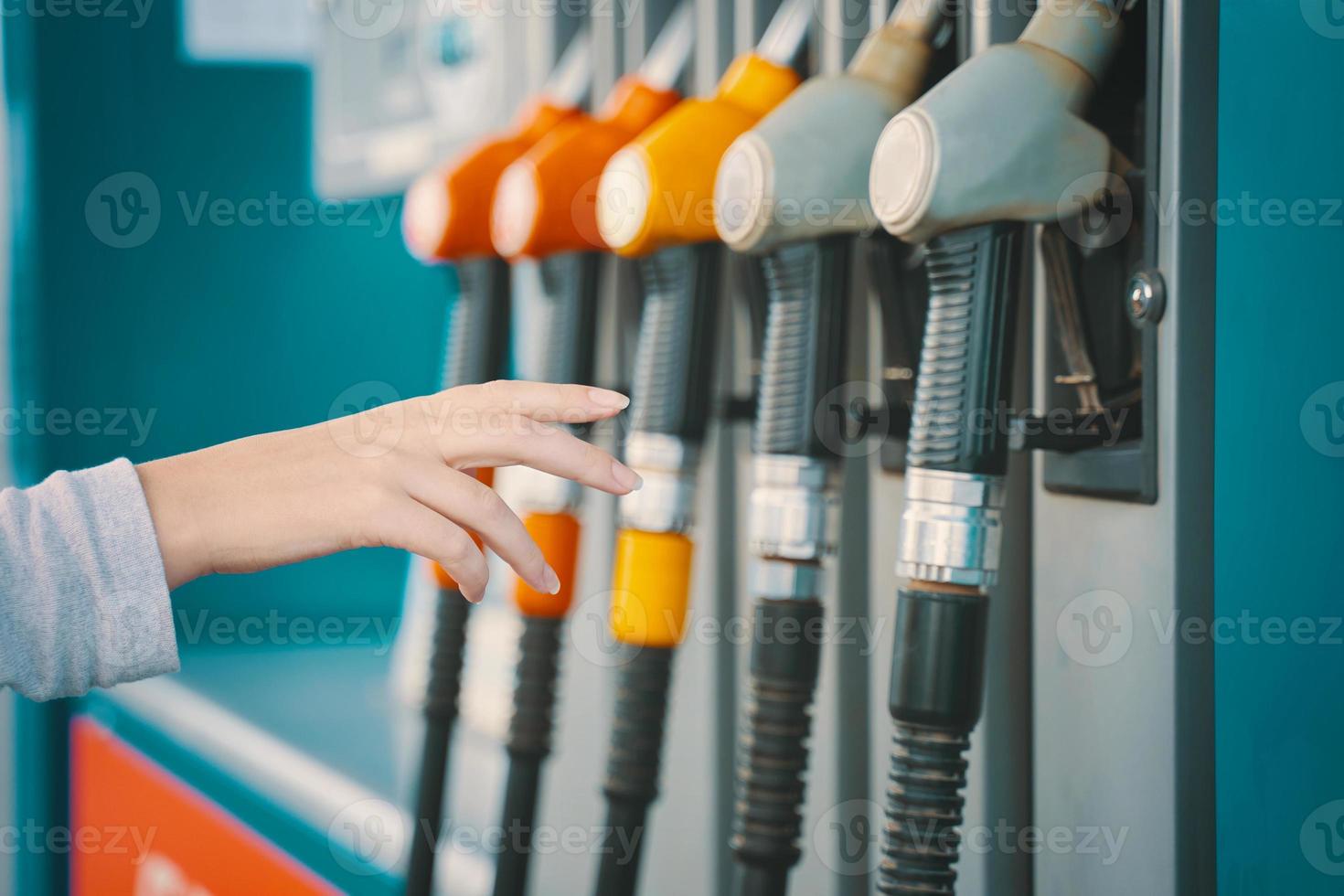 A human hand reaches for the gas pump filling nozzle photo