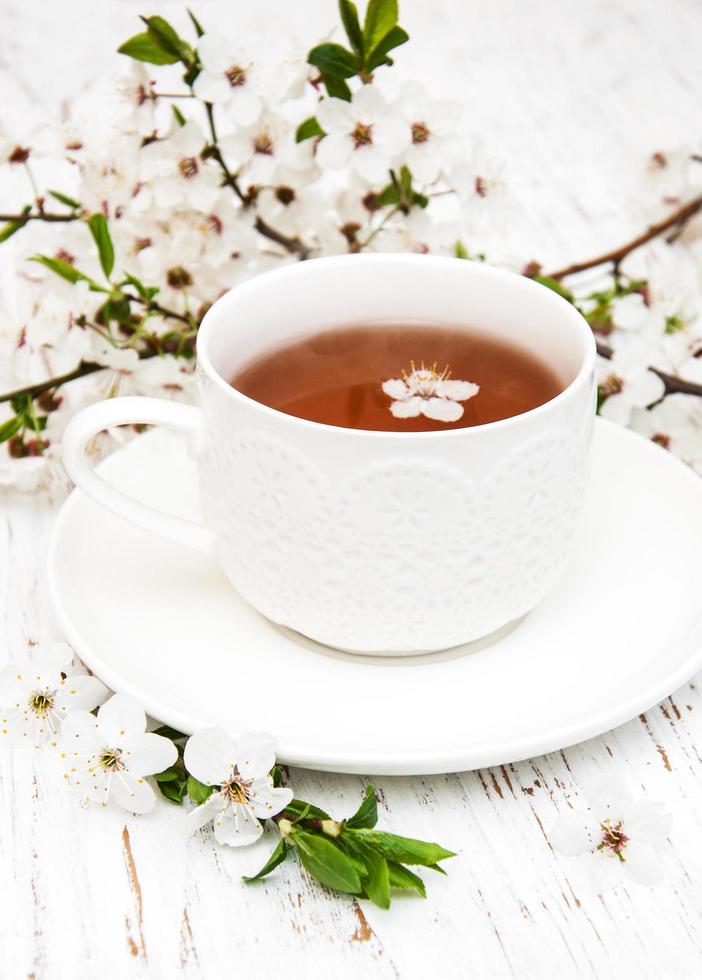 Cup of tea and spring apricot blossoms on a wooden background photo
