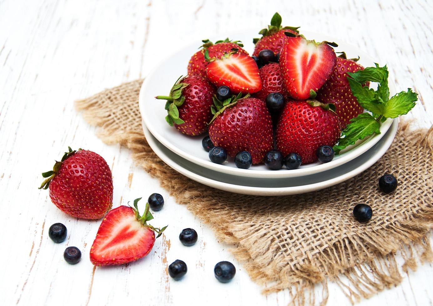Plate with blueberries and strawberries on an old wooden background photo