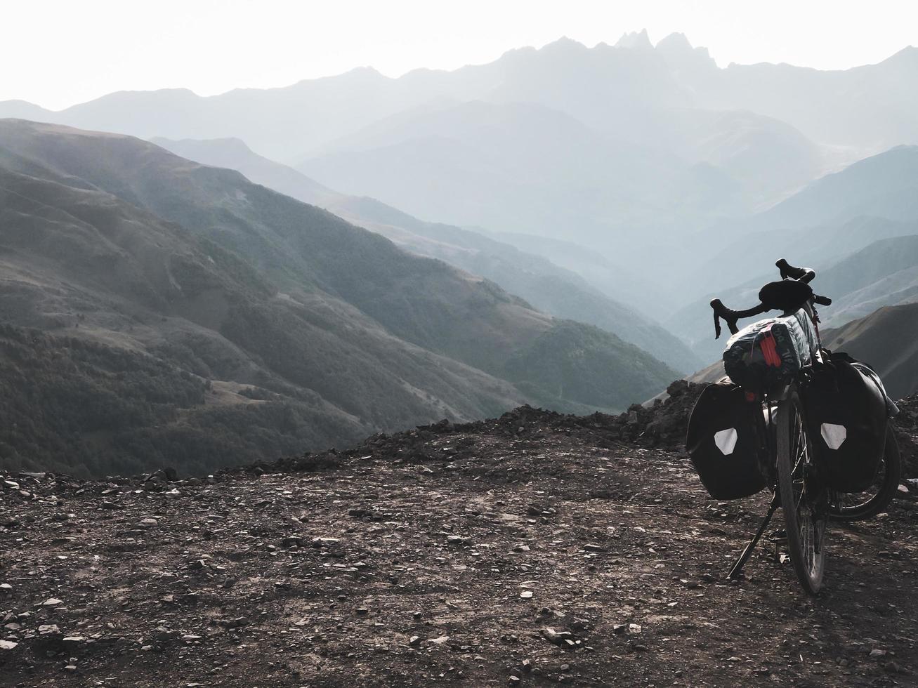 Loaded touring bicycle stands with moody dramatic panoramic mountain view and no cyclist photo