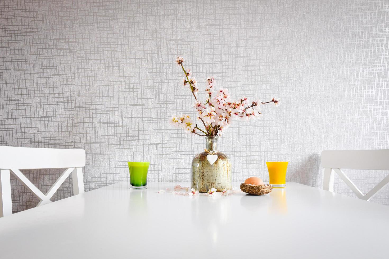 Green and yellow cup set up with fresh daisies in decorative vase on table photo