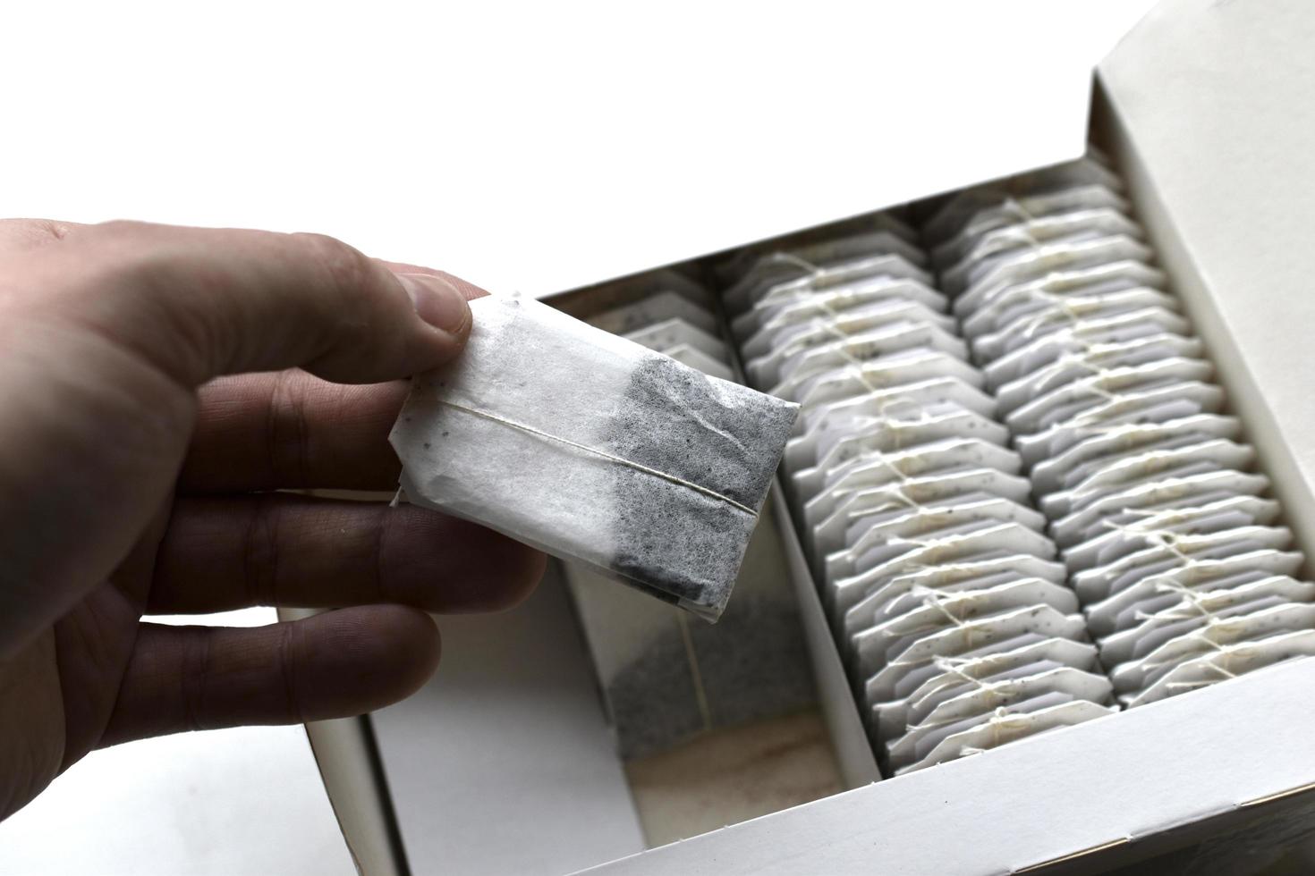 una caja de deliciosas bolsitas de té blanco con una mano foto