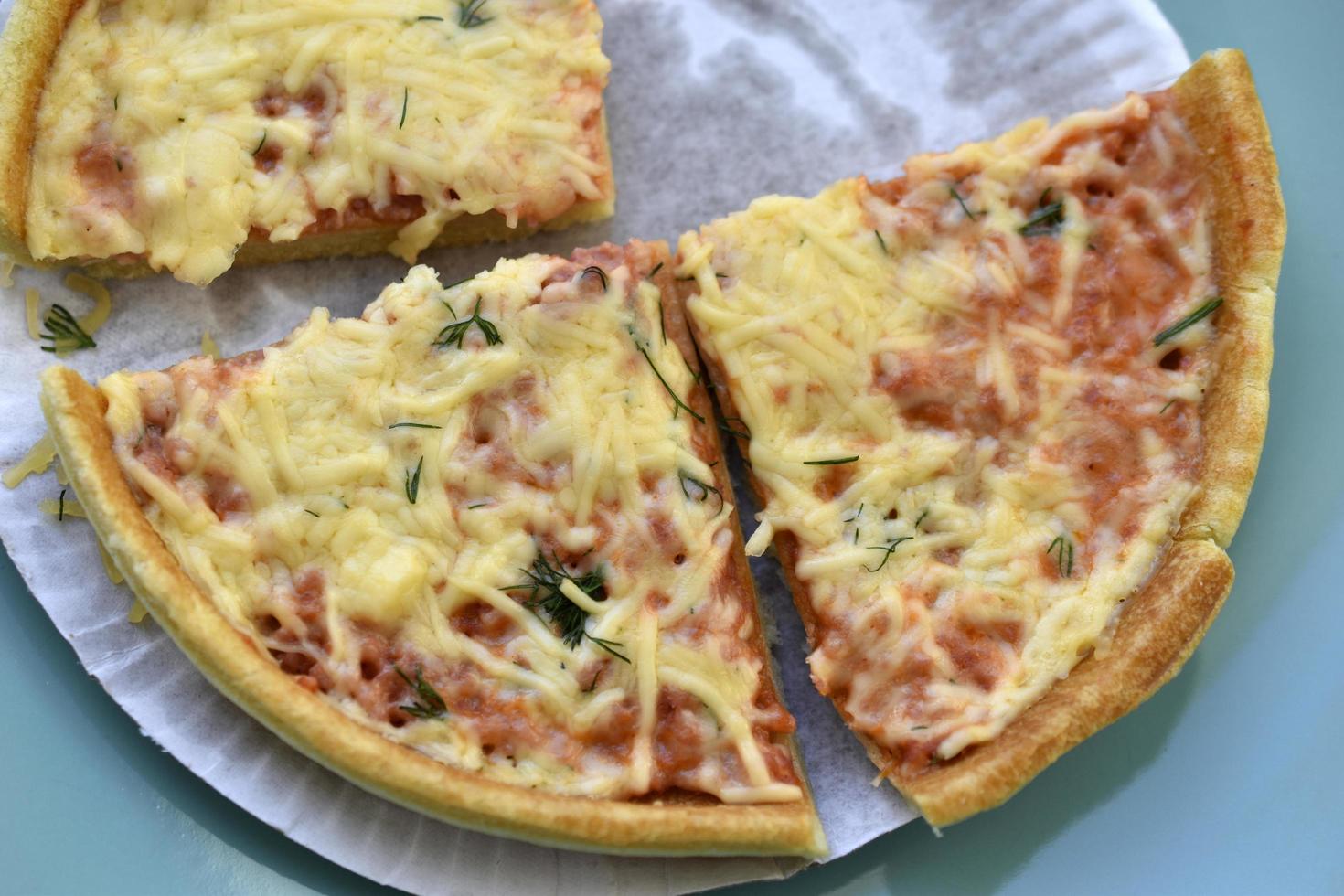 Cheap little pizza with cheese close-up on a plate photo