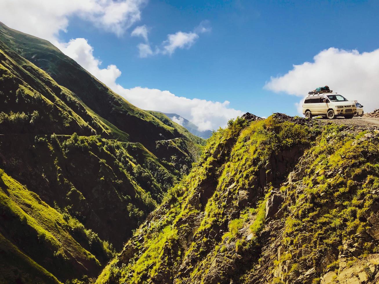 Tusheti, Georgia 2020: dos vehículos turísticos 4x4 girando en la carretera Tusheti con un fondo de valle peligroso foto