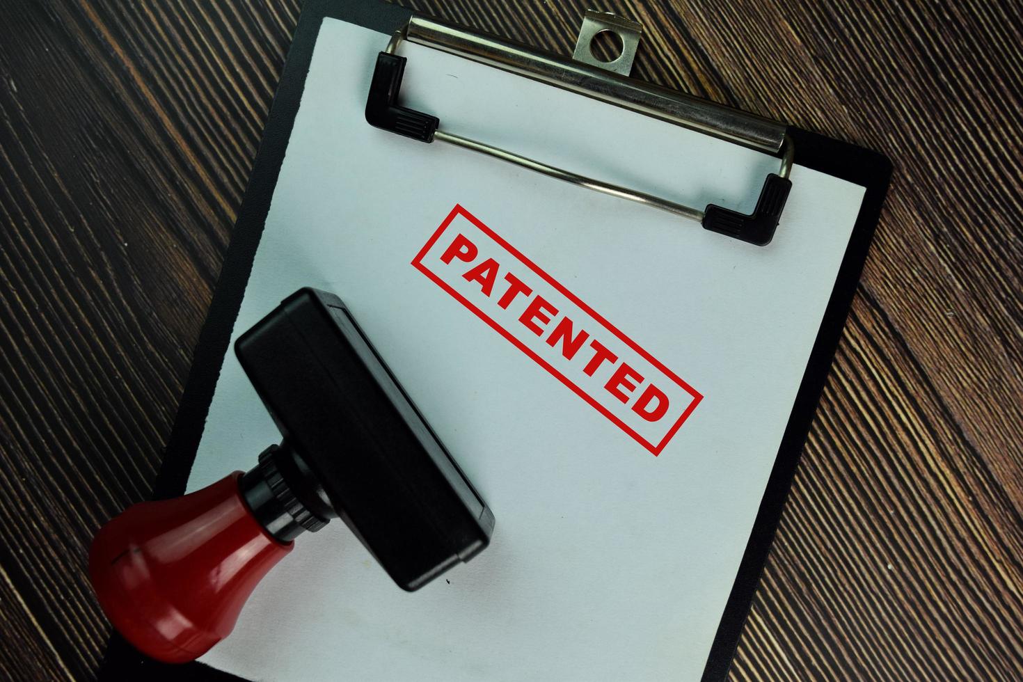 Red handled rubber stamper and patented text isolated on wooden table photo