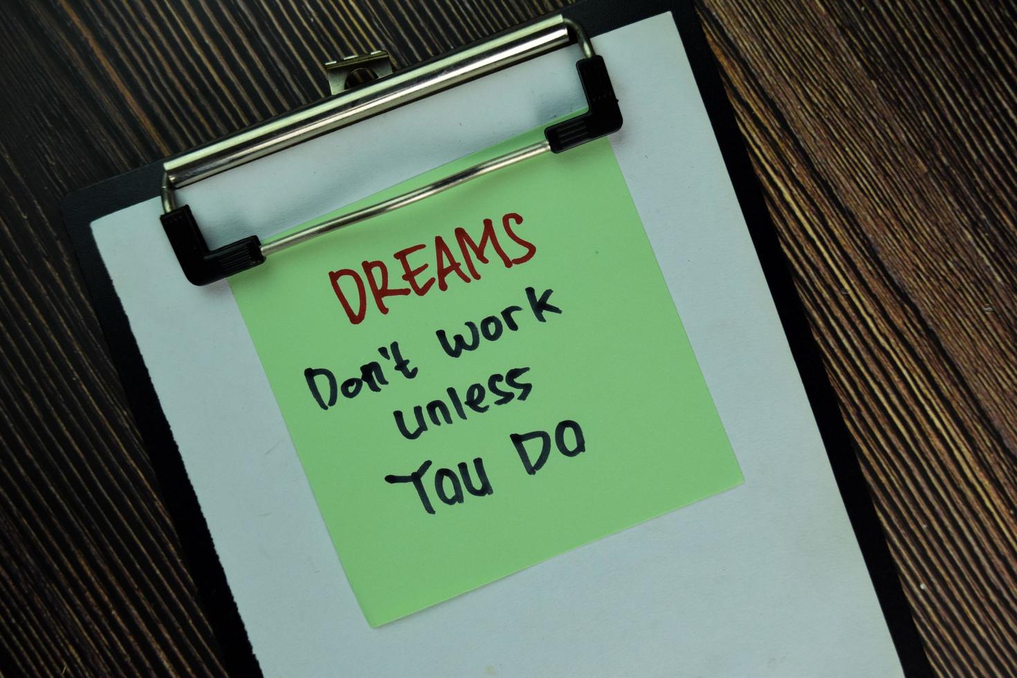 Dreams don't work unless you do written on sticky notes isolated on wooden table photo