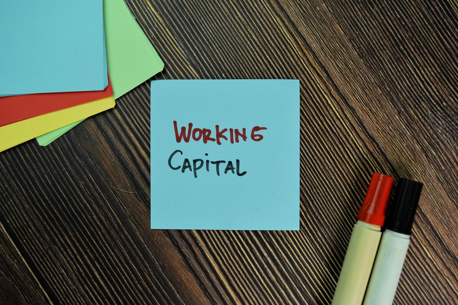 Working capital written on sticky notes isolated on wooden table photo