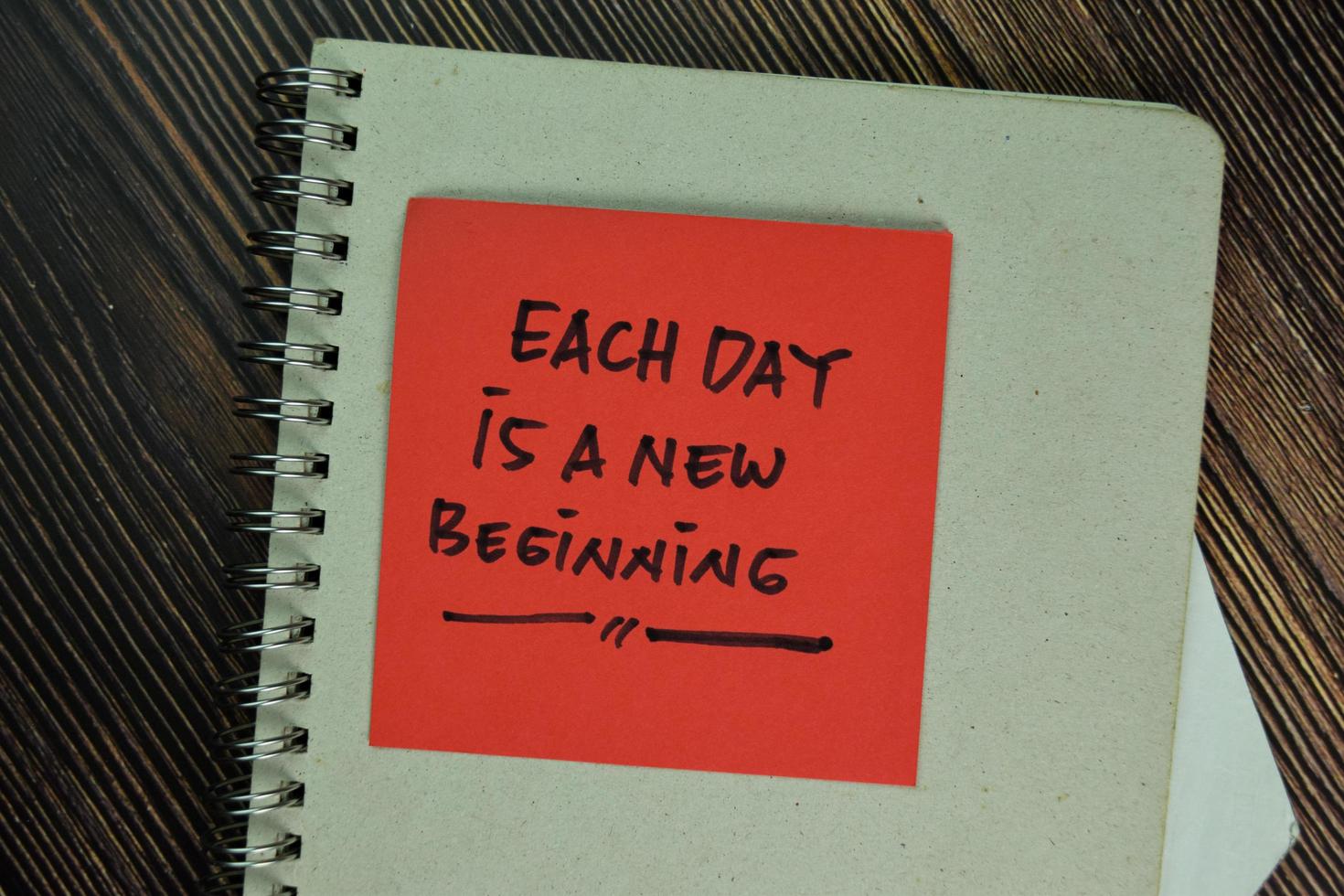 Each day is a new beginning written on sticky notes isolated on wooden table photo