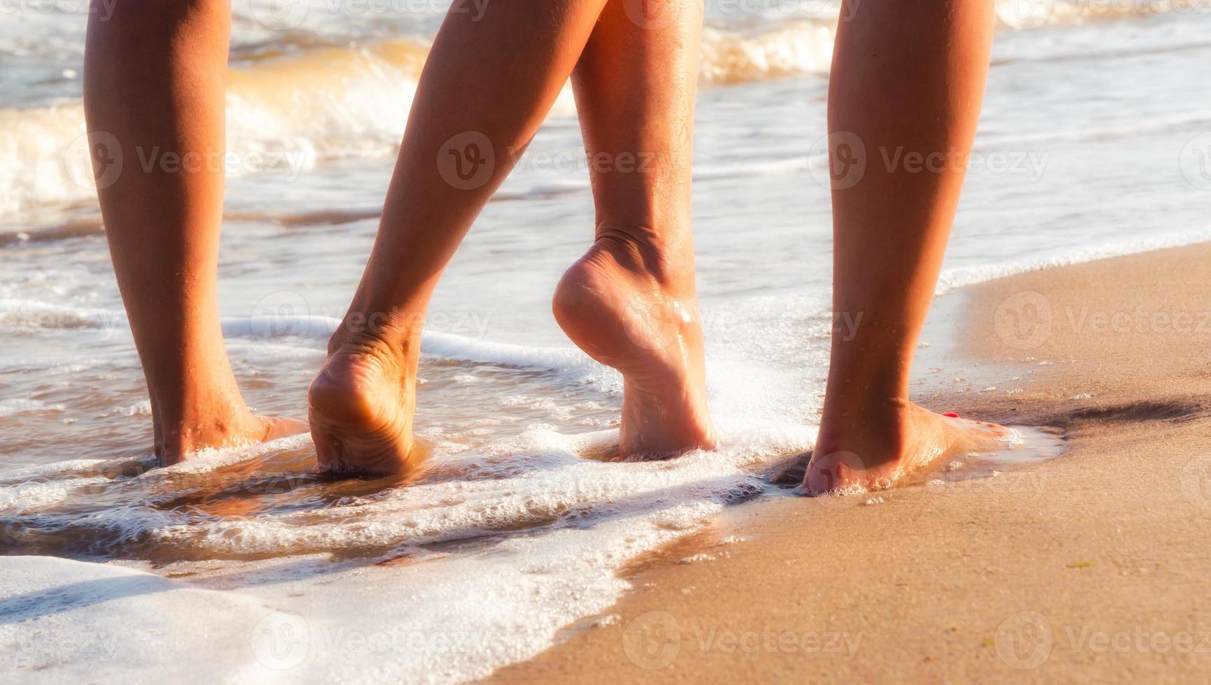 Two people walking with bare feet on sand photo