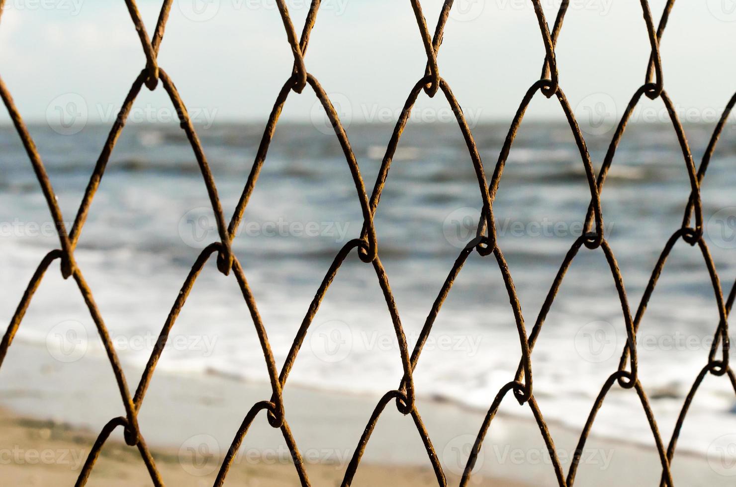 Mesh wire fence with a beach background photo