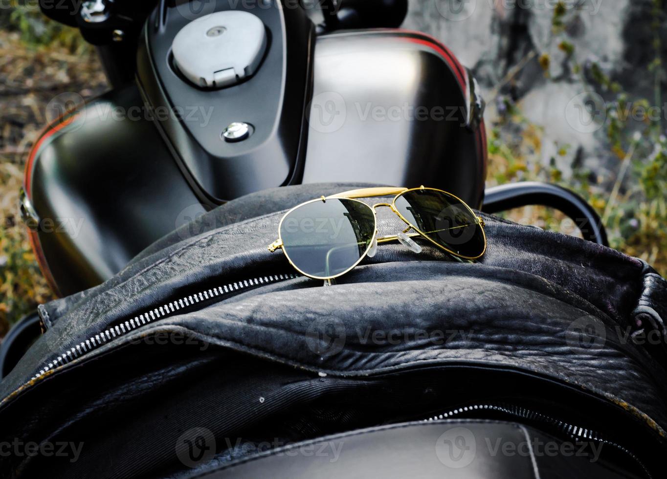 Gafas de sol en una chaqueta de cuero en un asiento de motocicleta. foto