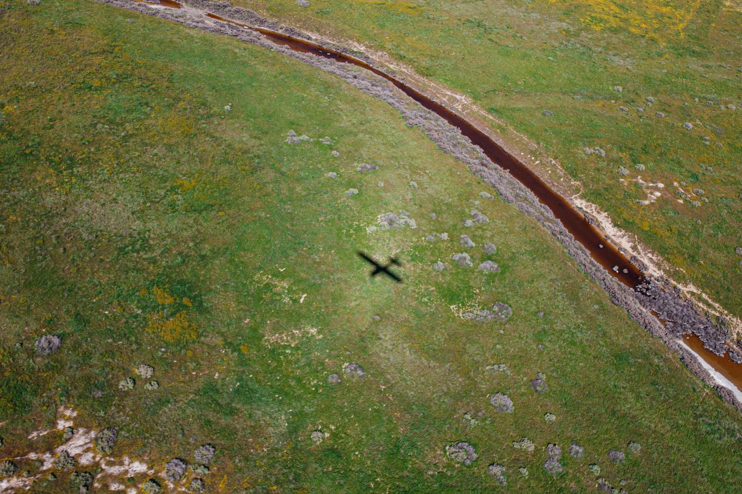 Sombra de un avión sobre campo rural verde foto