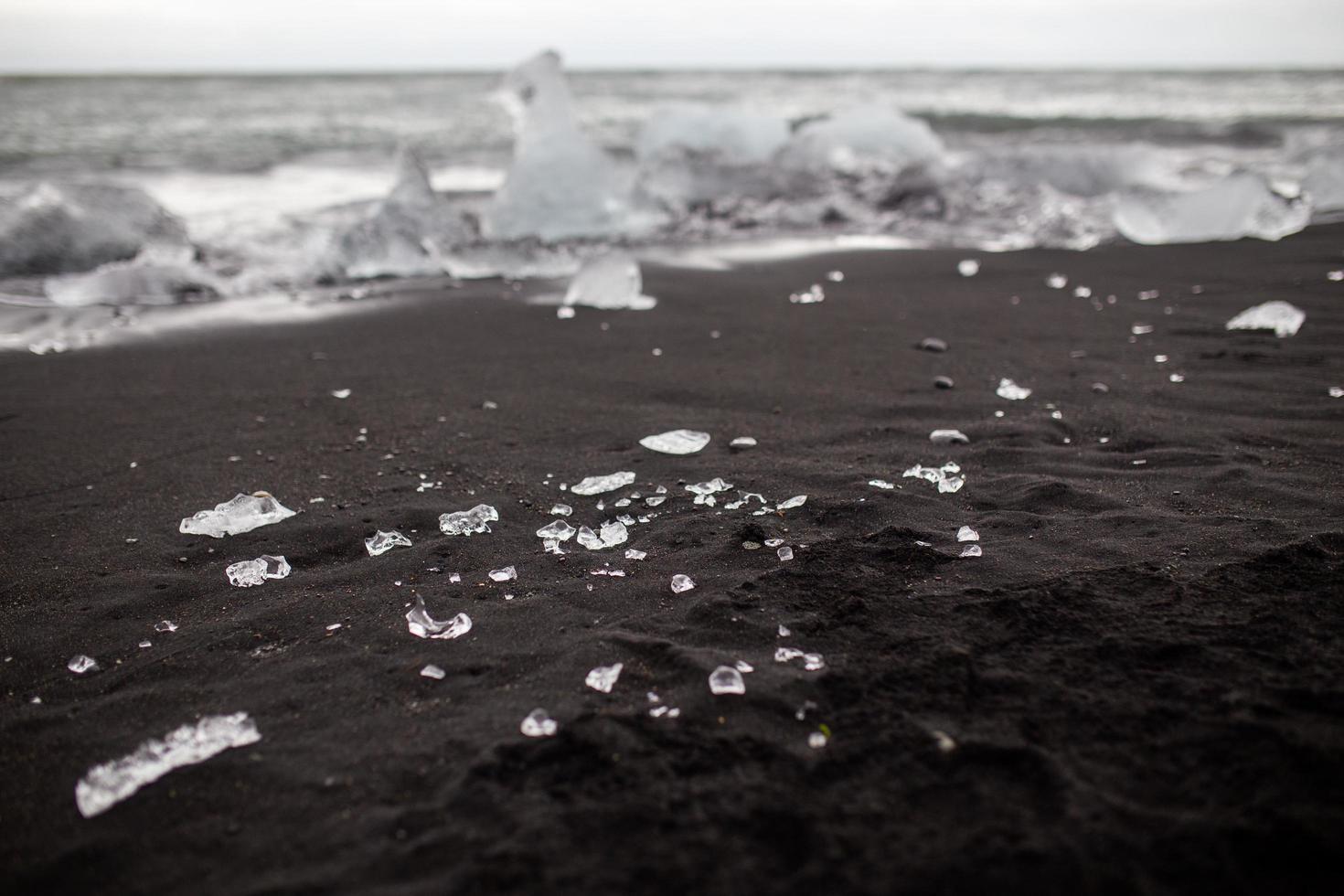 Small ice pieces on black sand beach in Vik, Iceland photo
