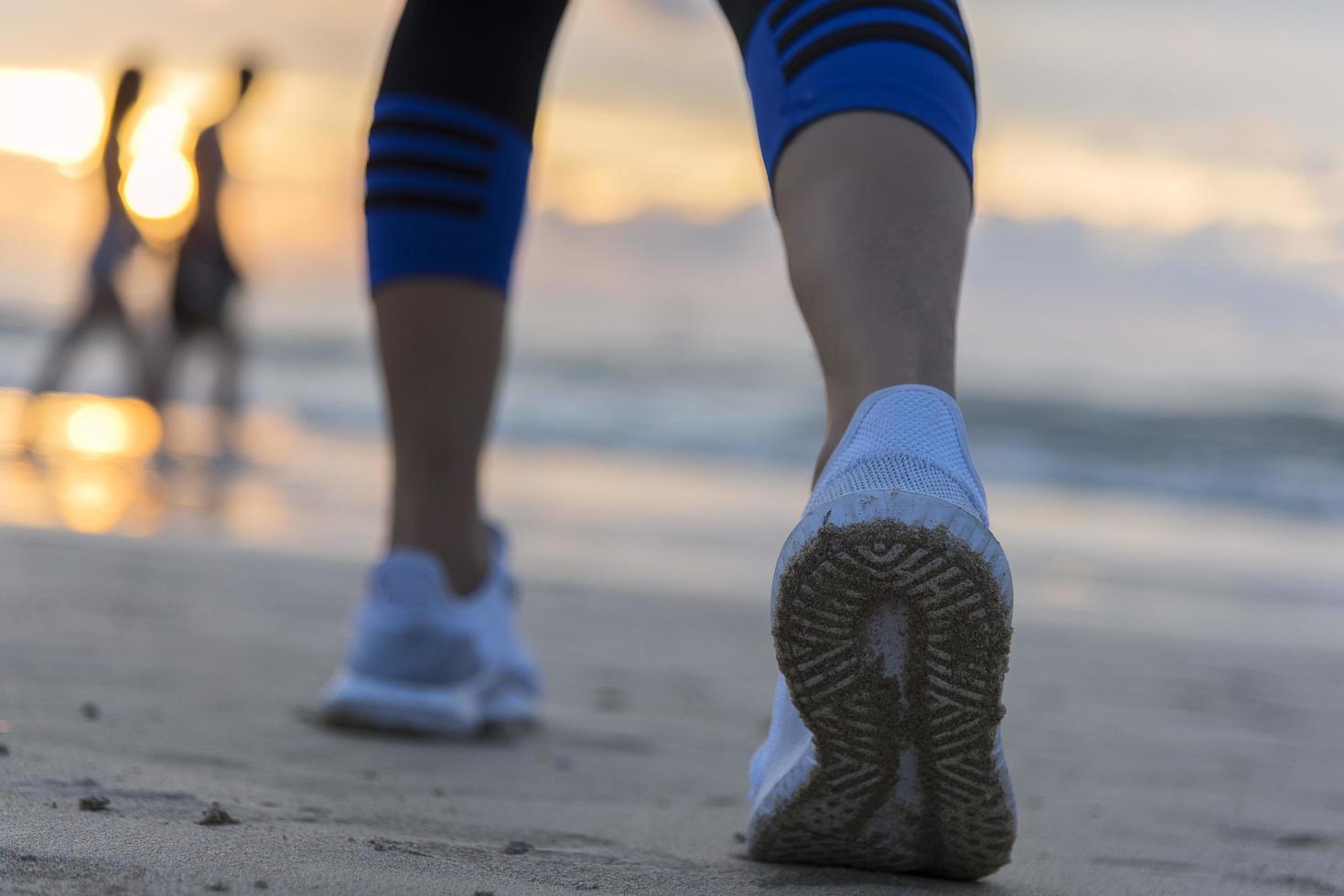 Woman running on the beach at sunrise closeup on the shoe. Patong beach, Phuket, Thailand photo