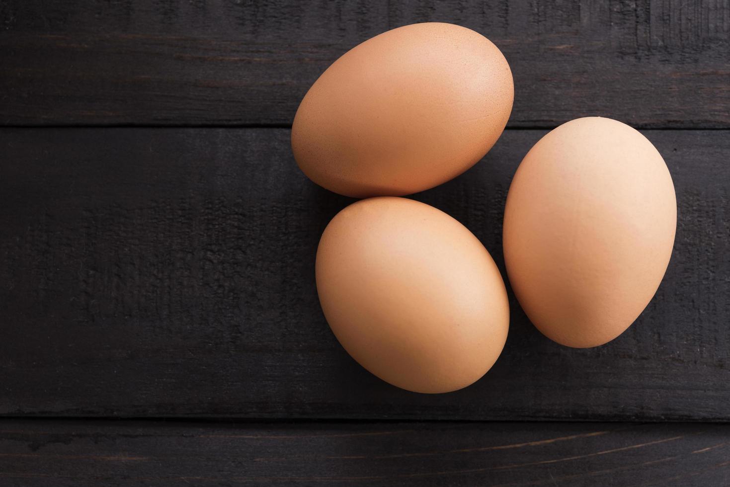 Tres huevos de gallina frescos en una mesa de madera foto