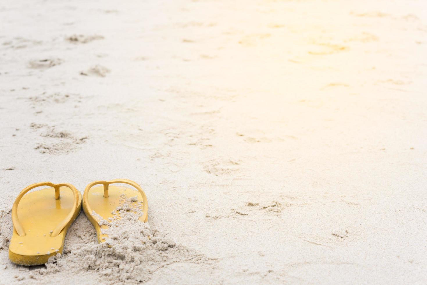 sandalias amarillas en la playa durante el verano foto