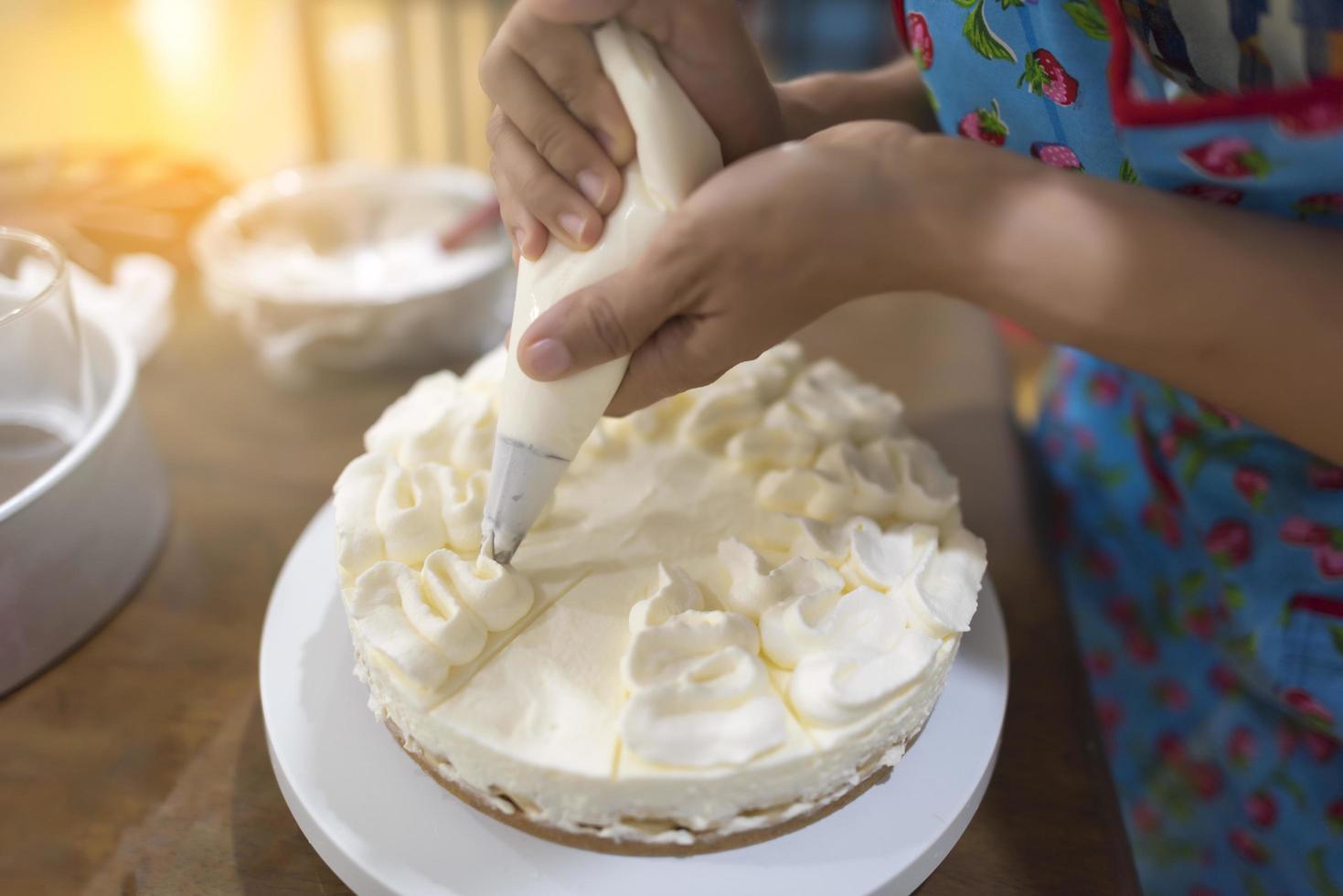 Mano de mujer decorando un pastel con una bolsa de crema pastelera foto