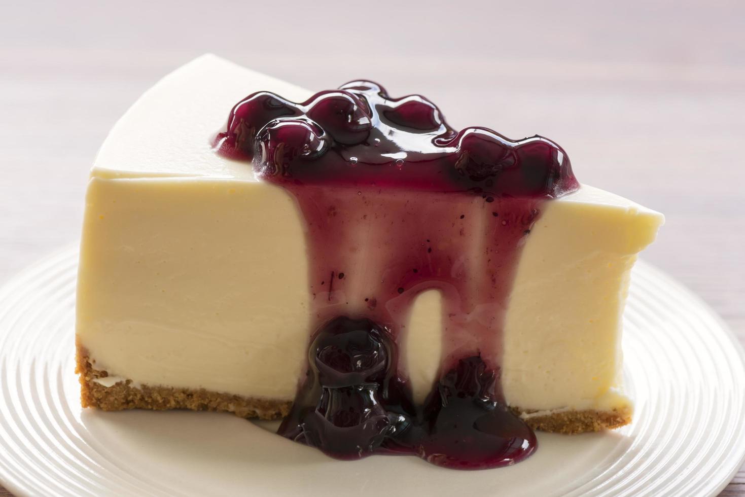 Tarta de queso con crema de arándanos en una placa blanca sobre una mesa de madera foto