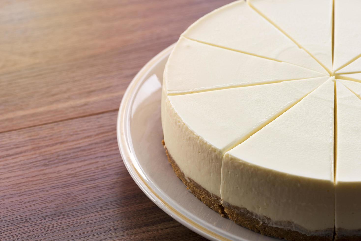 Tarta de queso en un plato blanco sobre una mesa de madera foto
