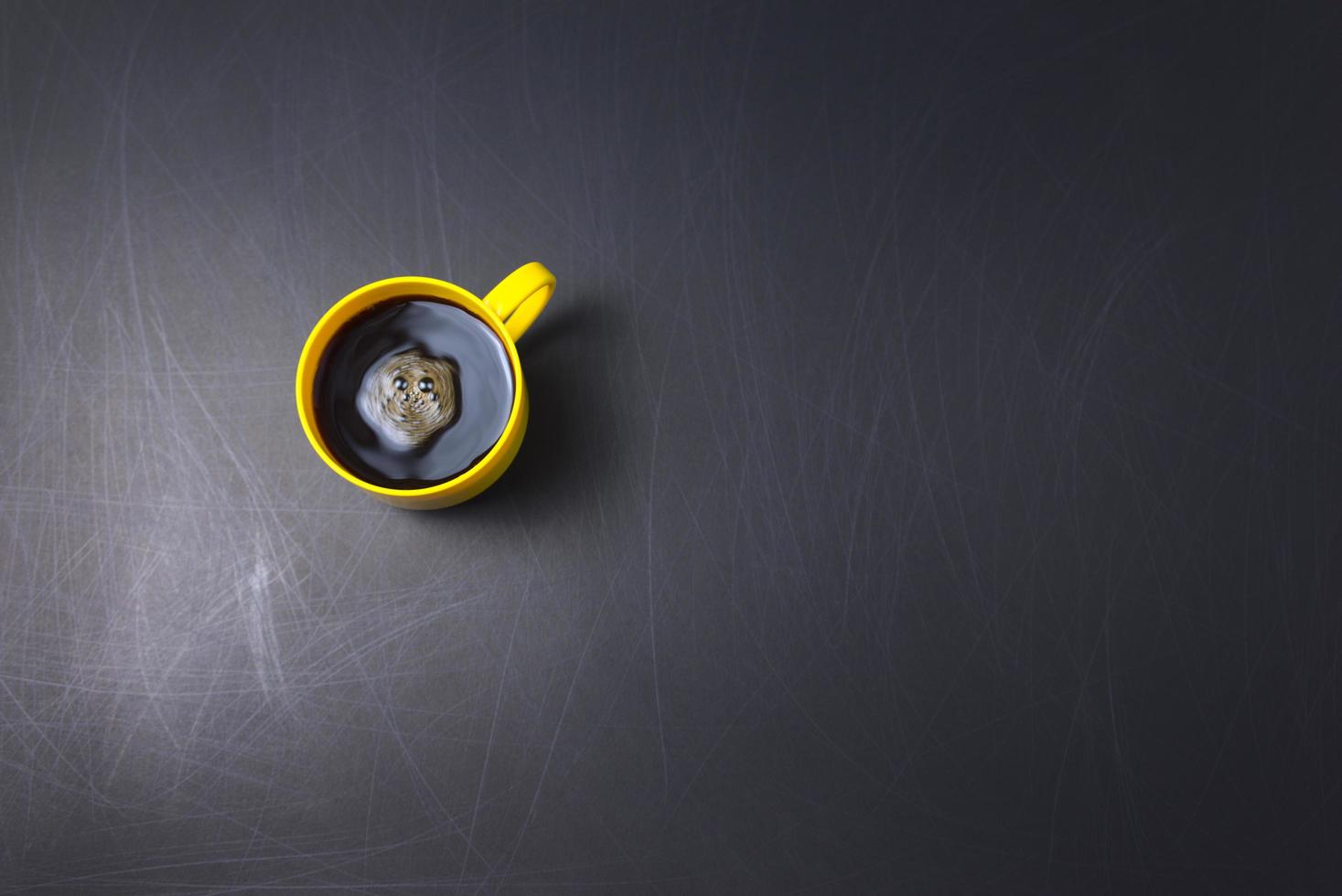 Black coffee with clockwise stir flat lay on scratched black background photo