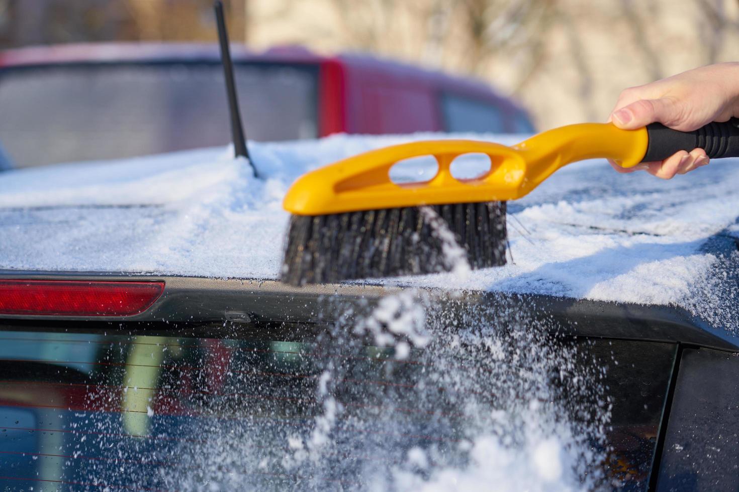 quitando la nieve del techo de un coche foto