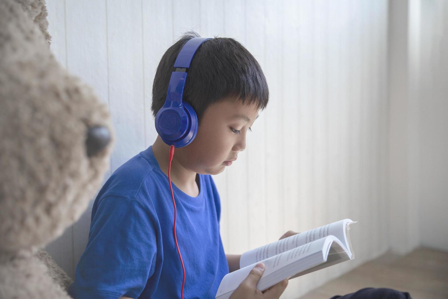 Boy listening to and reading a book photo