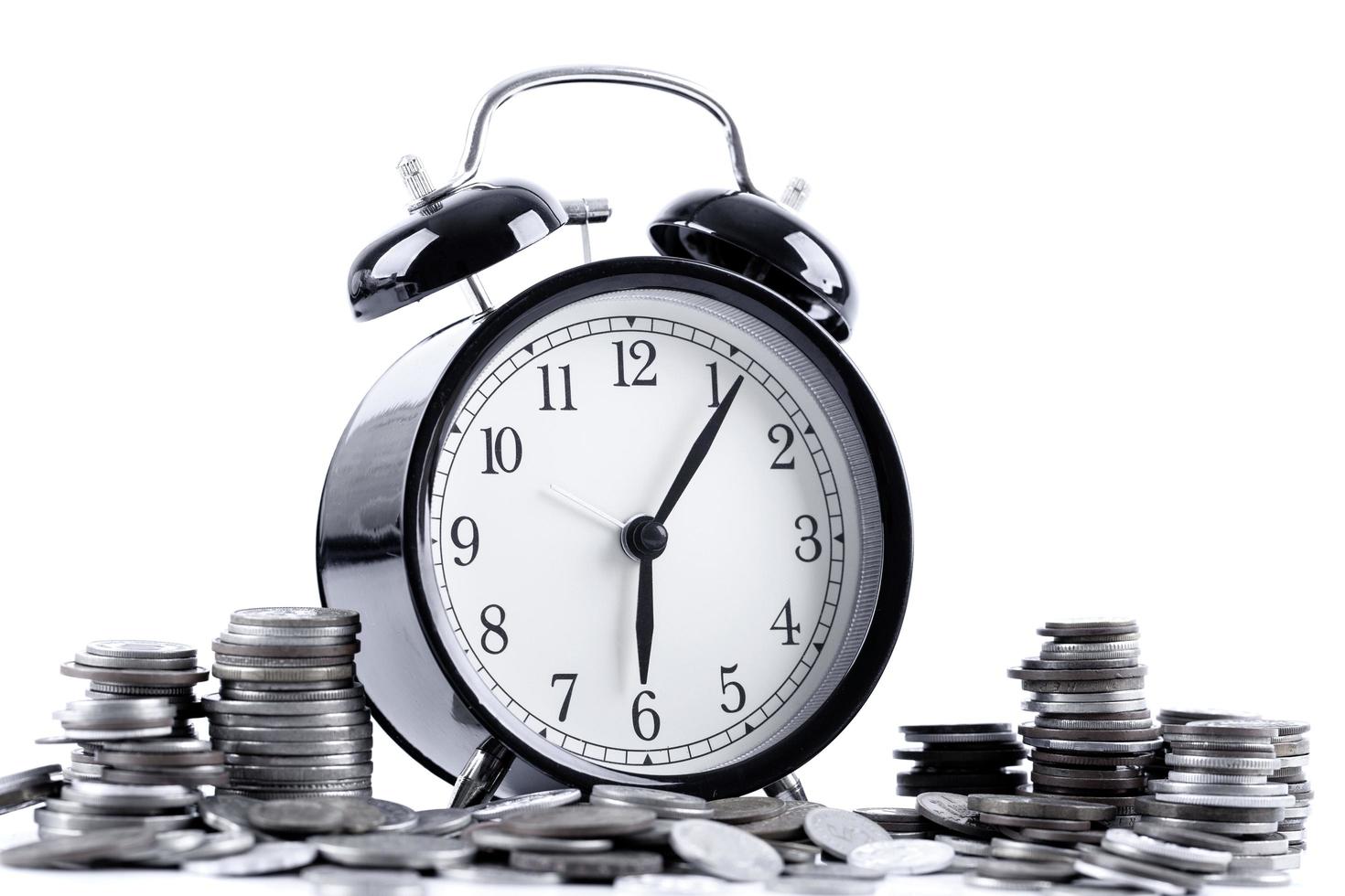 Black alarm clock and stack of coins photo