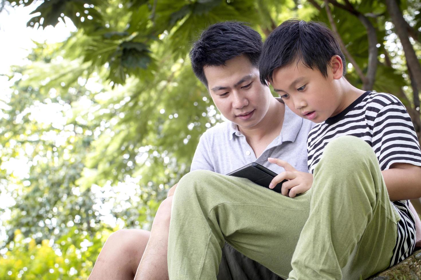 Father and son reading outside photo