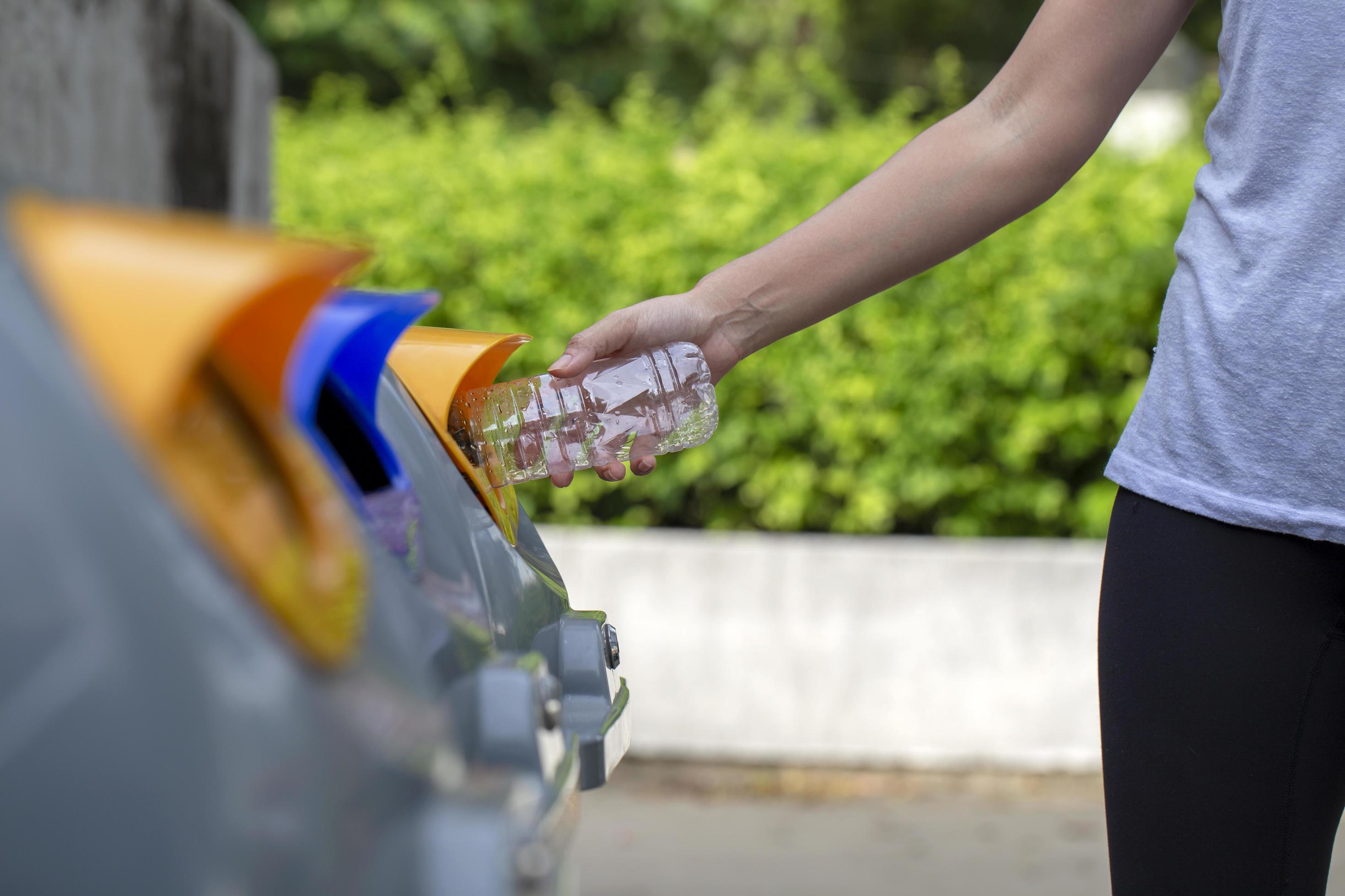mujer reciclando una botella de plastico foto