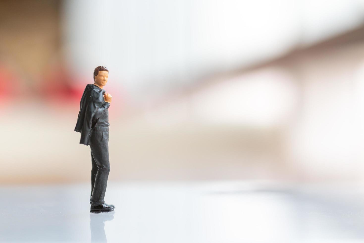 Miniature businessman standing on empty space for text photo