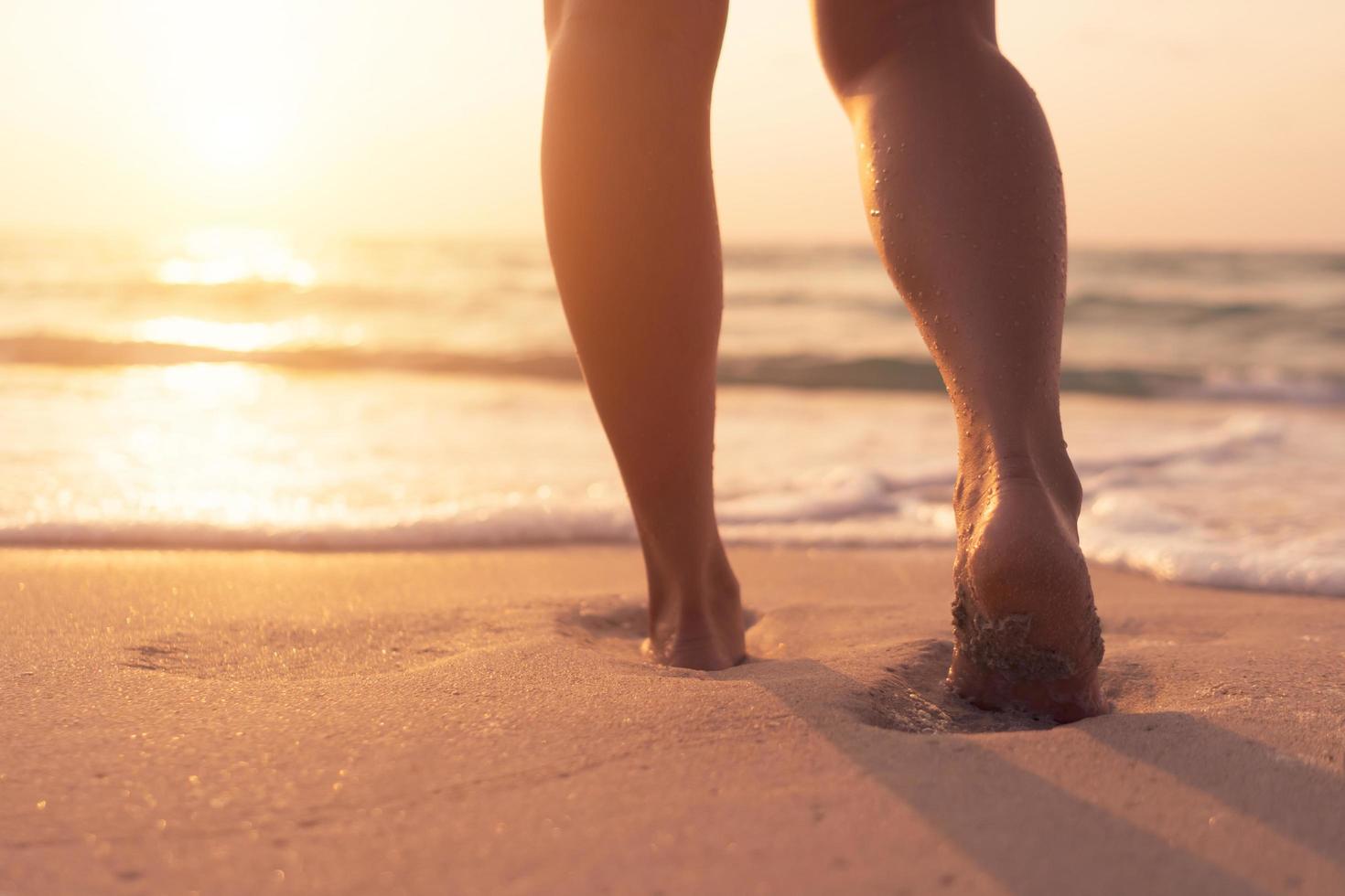 Pies caminando lentamente, vida y relajación en una playa tropical de arena con un fondo de cielo azul foto