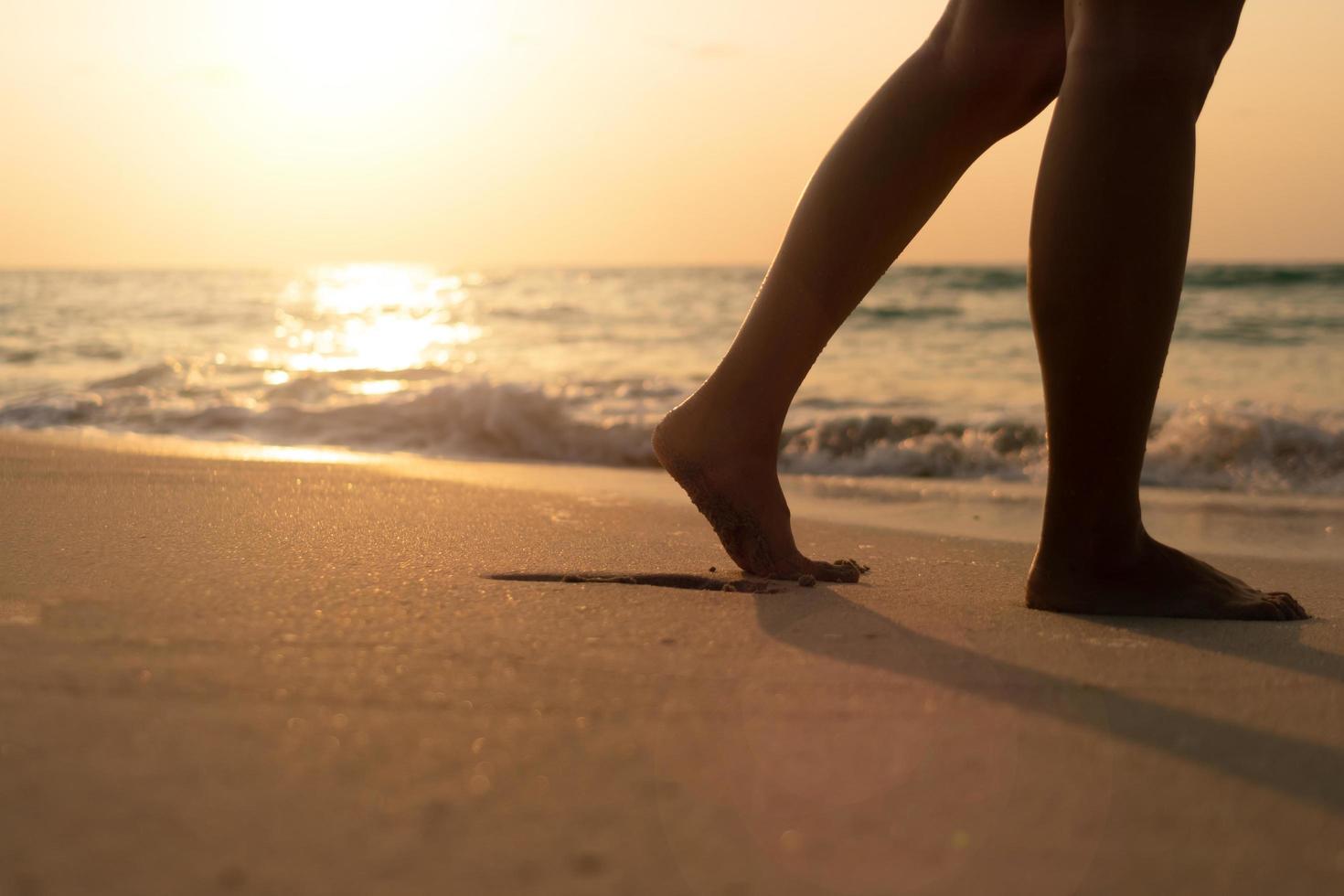 Pies caminando lentamente, vida y relajación en una playa tropical de arena con un fondo de cielo azul foto