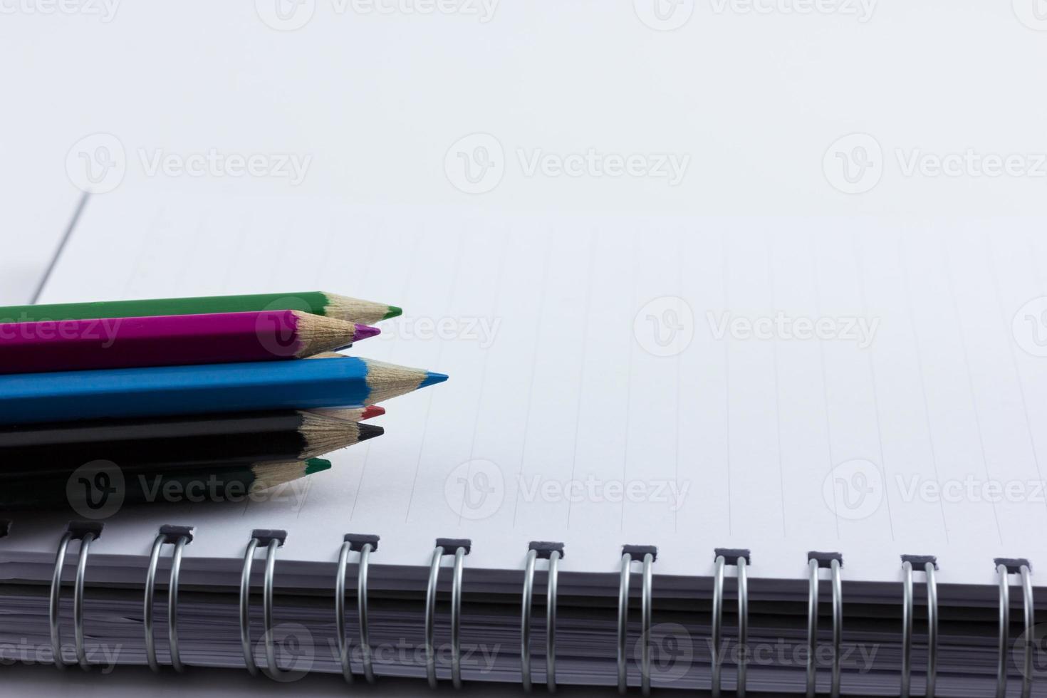 Cuaderno en blanco aislado con lápices de colores foto