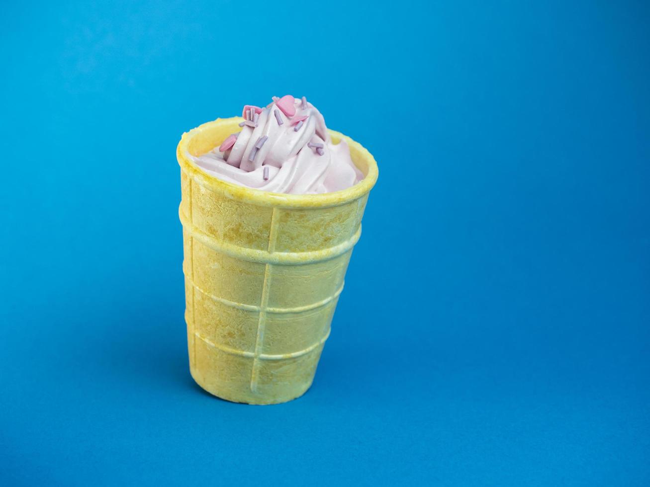 helado suave rosa espolvoreado con corazones de color rosa sobre un fondo azul foto