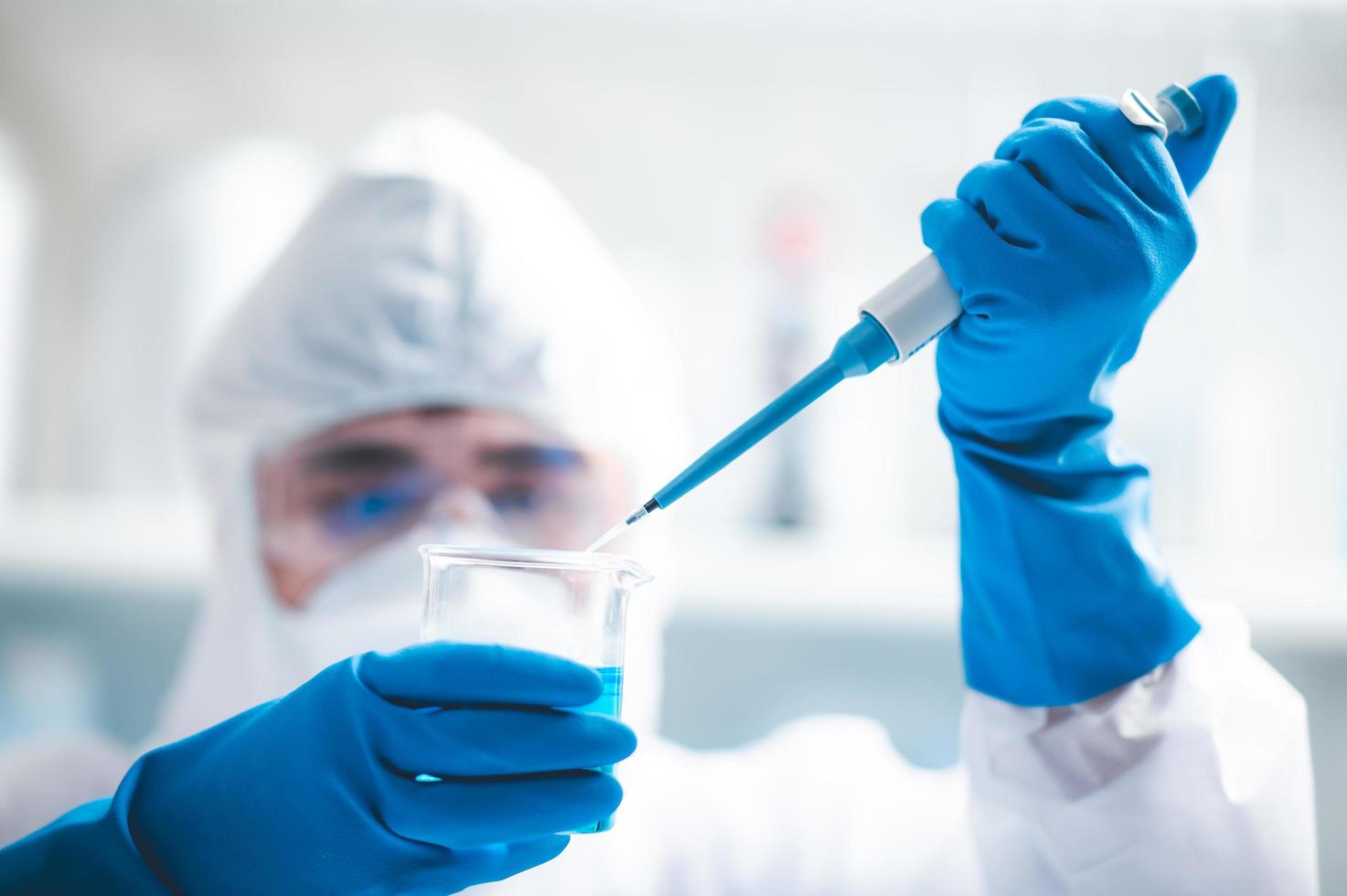 Researcher adding liquid to a beaker photo