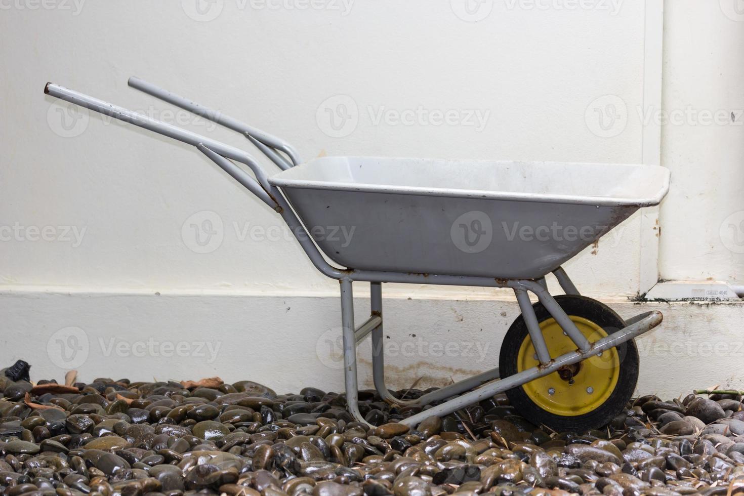 Yellow wheelbarrow on wet river stones photo