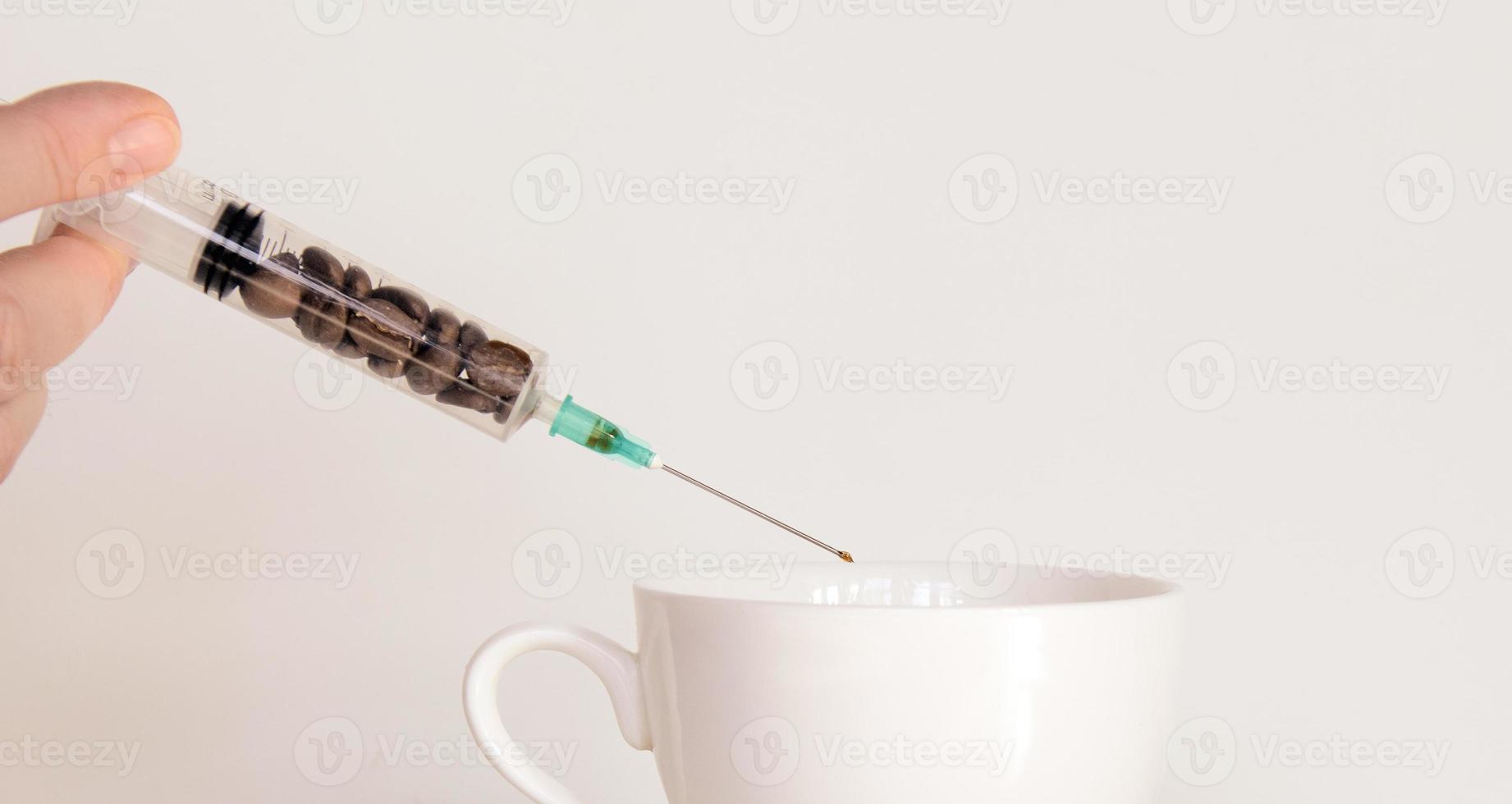 A woman's hand with a syringe containing coffee beans photo