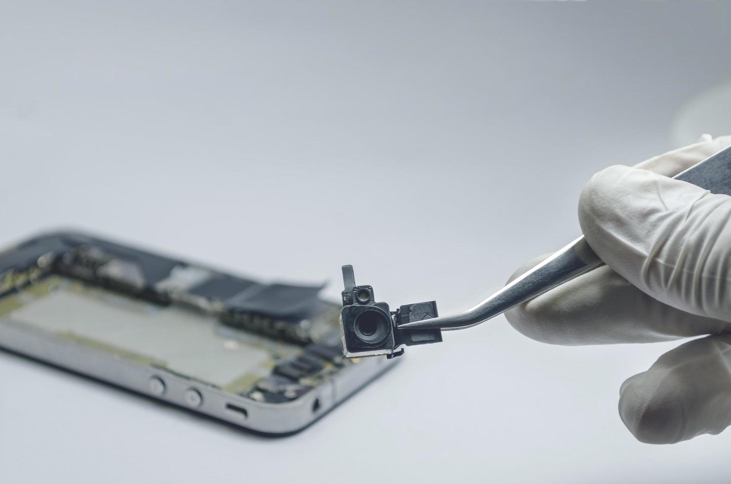 Close up of a professional technician repairing a camera phone with mini tools on a desk photo