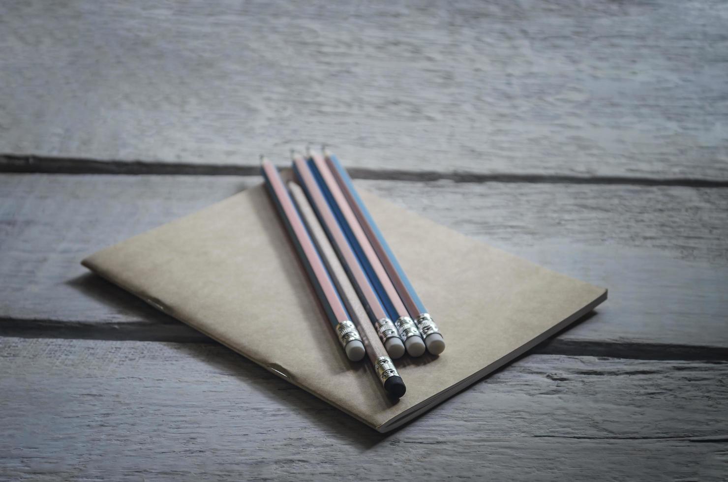 Pencils with a brown notebook placed on a wooden table photo