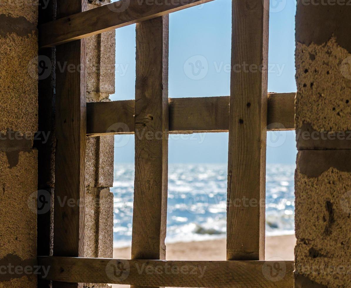 vista de la orilla del mar a través de una ventana tapiada foto
