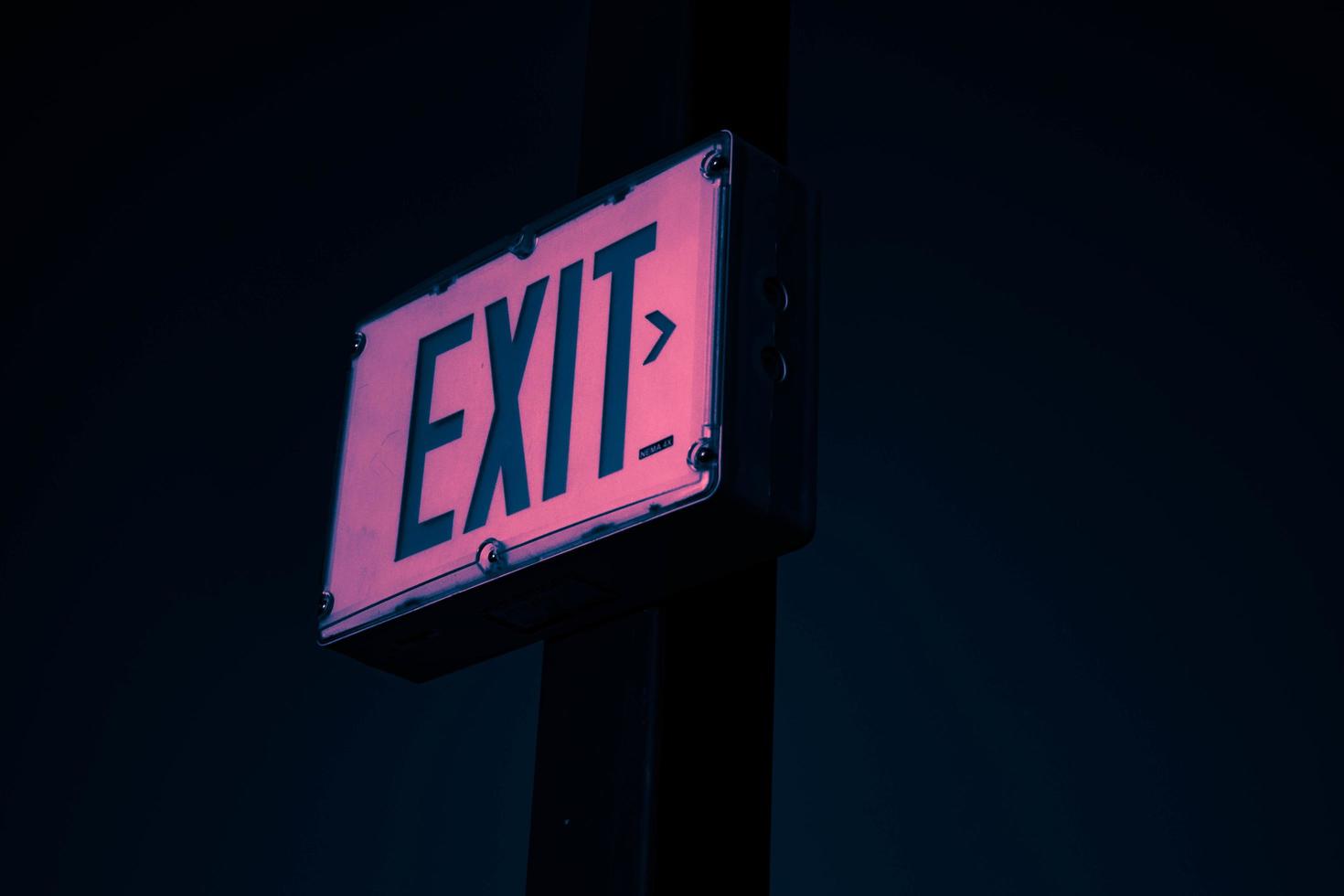 An exit sign at night reflecting pink tones photo