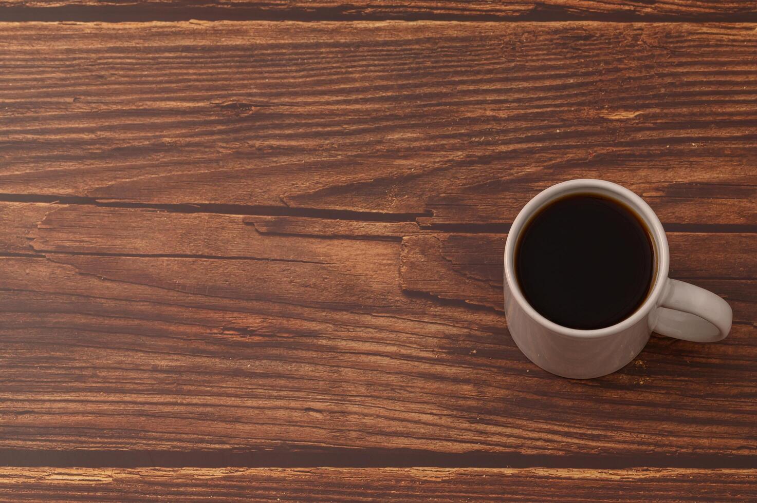 Taza de café llena de café en un escritorio de madera foto