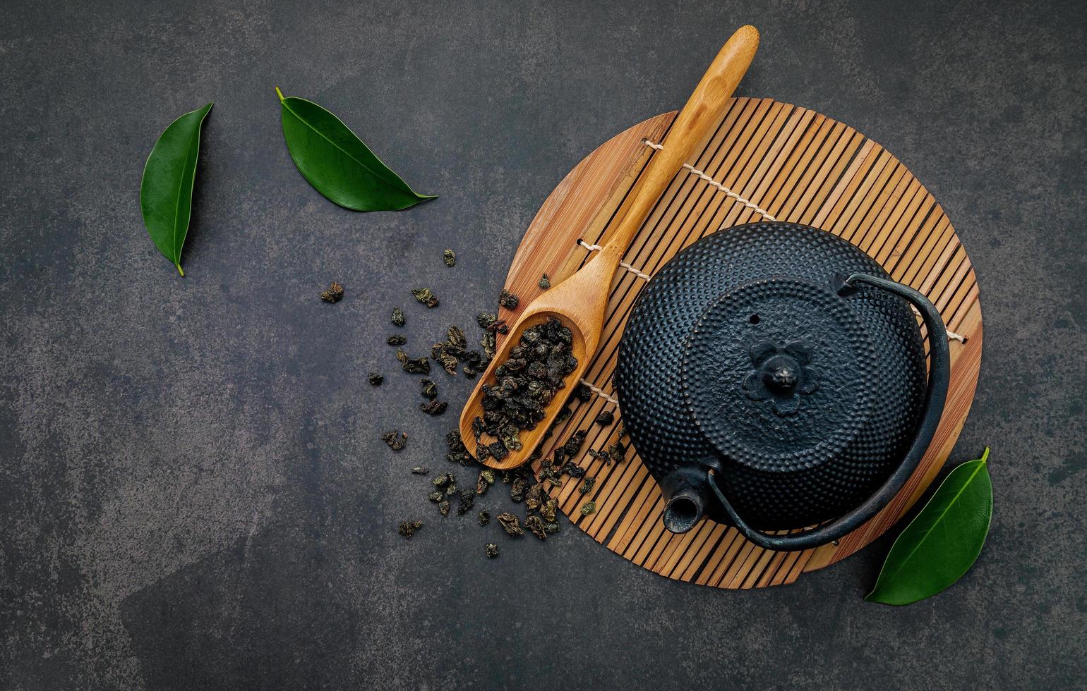 Tetera de hierro fundido negro con té de hierbas sobre un fondo de piedra oscura foto