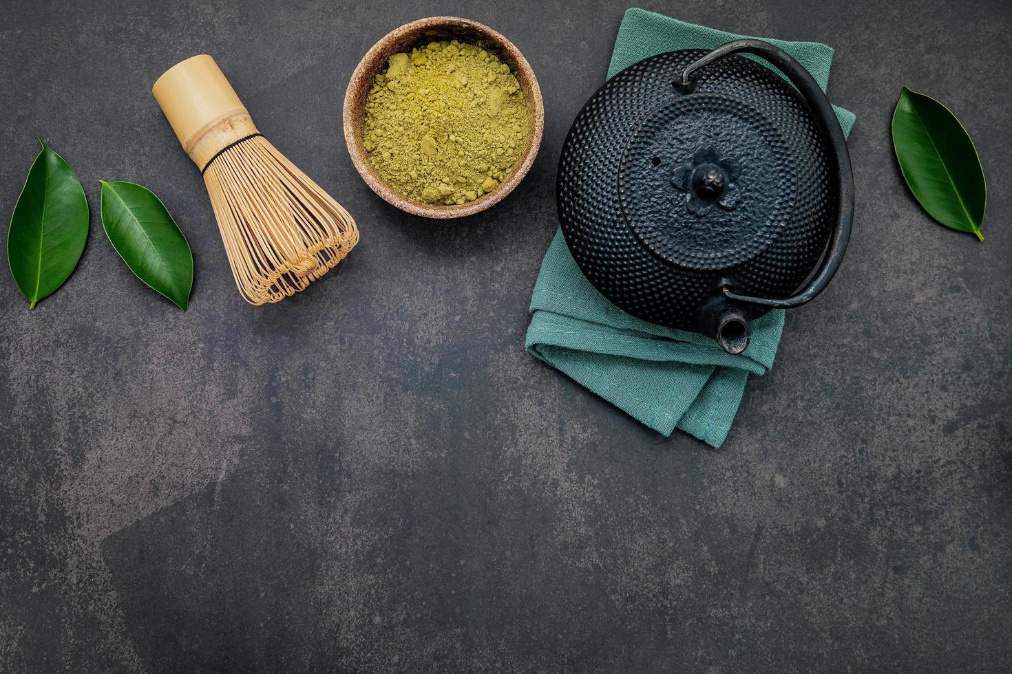 Black cast iron tea pot with herbal tea set up on a dark stone background photo