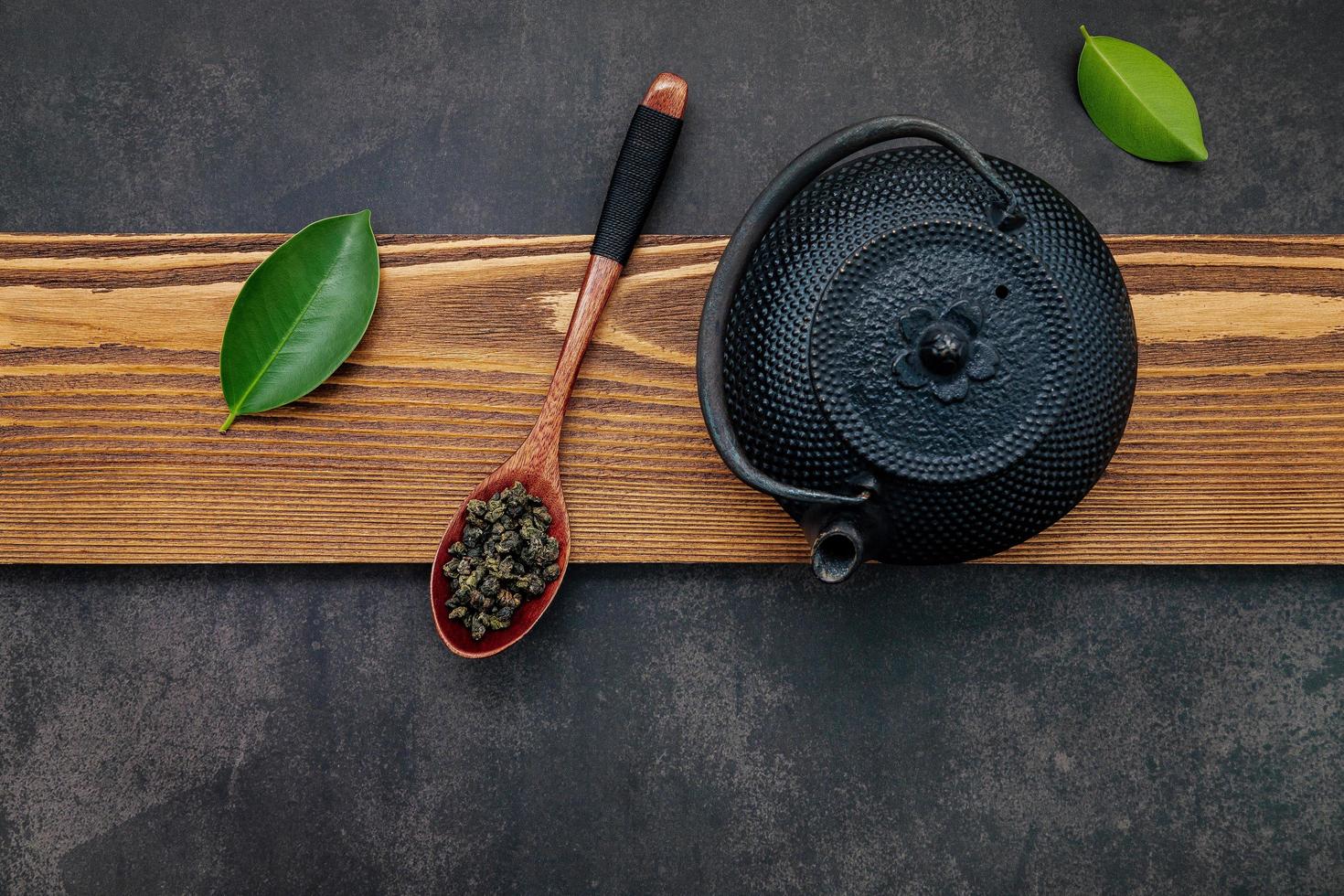 Black cast iron tea pot with herbal tea set up on a dark stone background photo