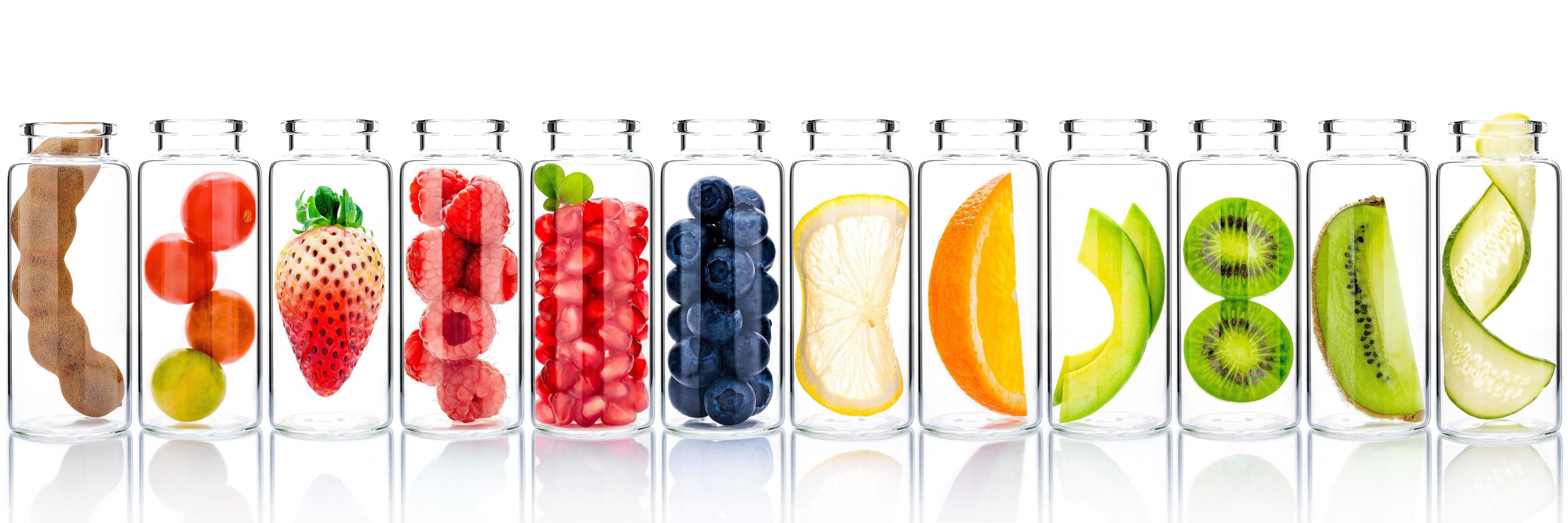 Homemade skincare with fruit ingredients of avocado, orange, blueberry, pomegranate, kiwi, lemon, strawberry, and raspberry in glass bottles isolated on a white background. photo