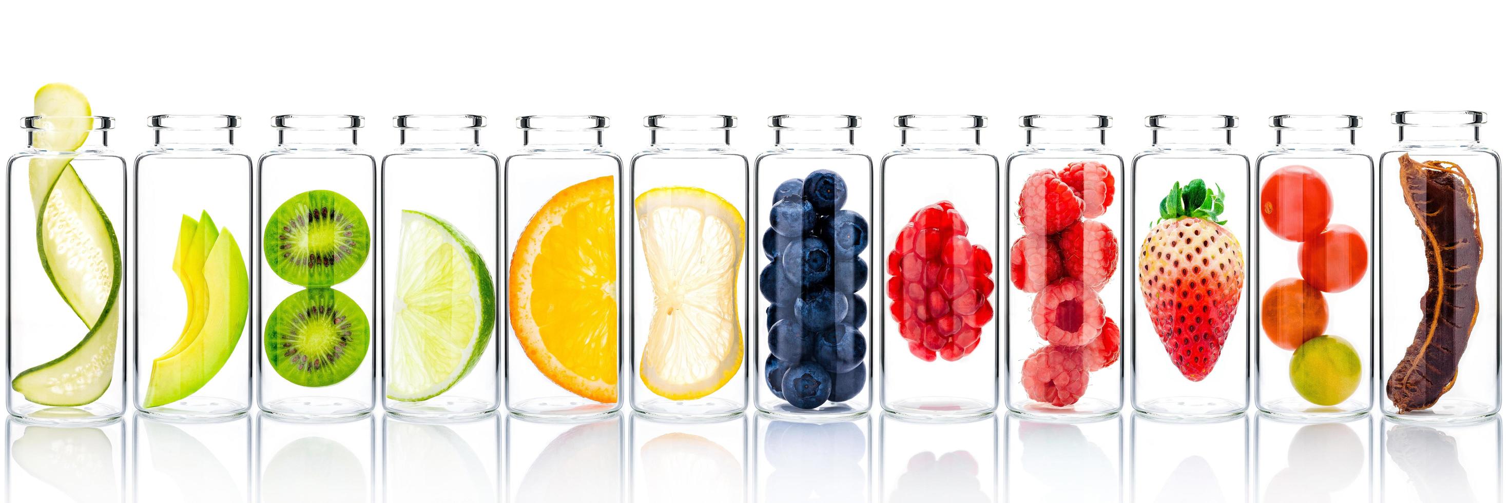 Cuidado de la piel casero con ingredientes de frutas de aguacate, naranja, arándano, granada, kiwi, limón, pepino, tamarindo, fresa y frambuesa en botellas de vidrio aisladas sobre fondo blanco. foto