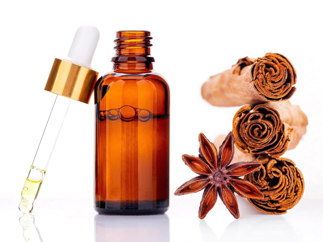 Cinnamon essential oil bottle with Ceylon cinnamon sticks and anise star isolated on a white background photo