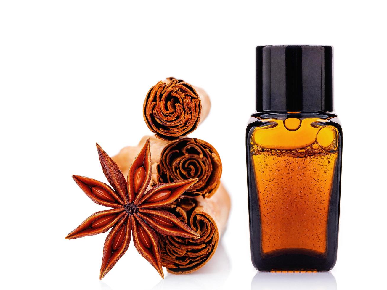 Cinnamon essential oil bottle with Ceylon cinnamon sticks and anise star isolated on a white background photo