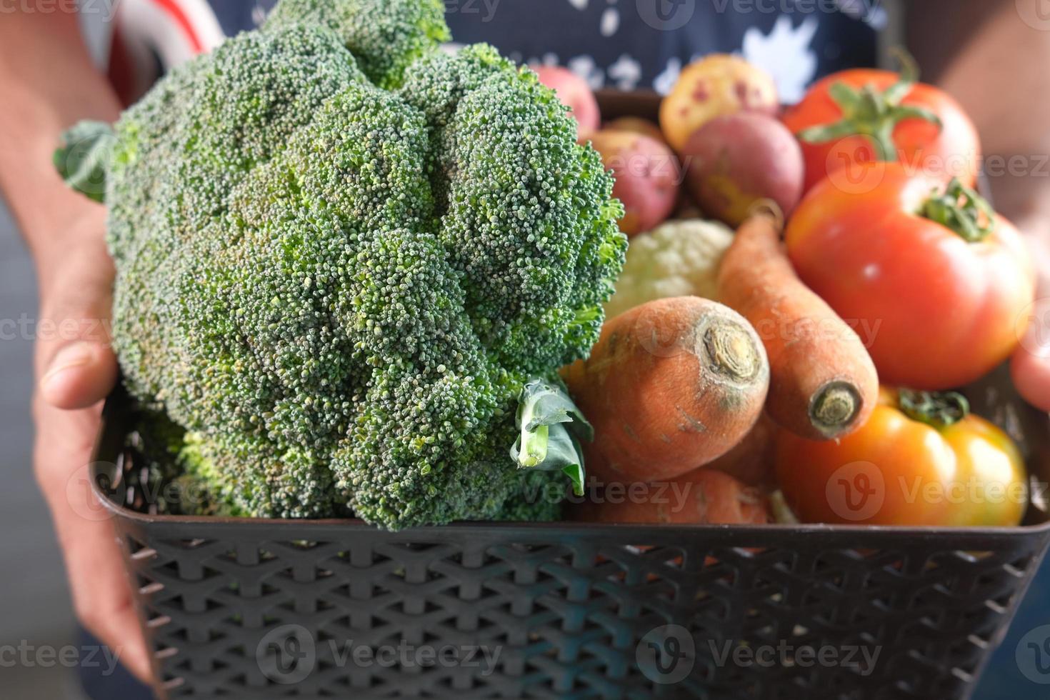 manos sosteniendo una caja de verduras foto